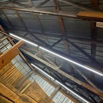 Looking up at the ceiling of a building with wooden beams and lights.