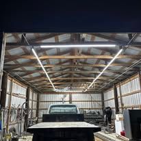 A truck is parked in a garage with lights on the ceiling.