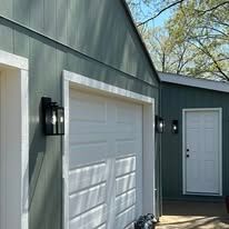 A couple of garages with white garage doors and white doors.