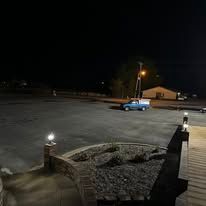 A blue truck is parked in a parking lot at night.