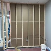 A room with a wall being built and a bucket on the floor.