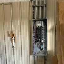 A electrical box is hanging on a wall in a room.