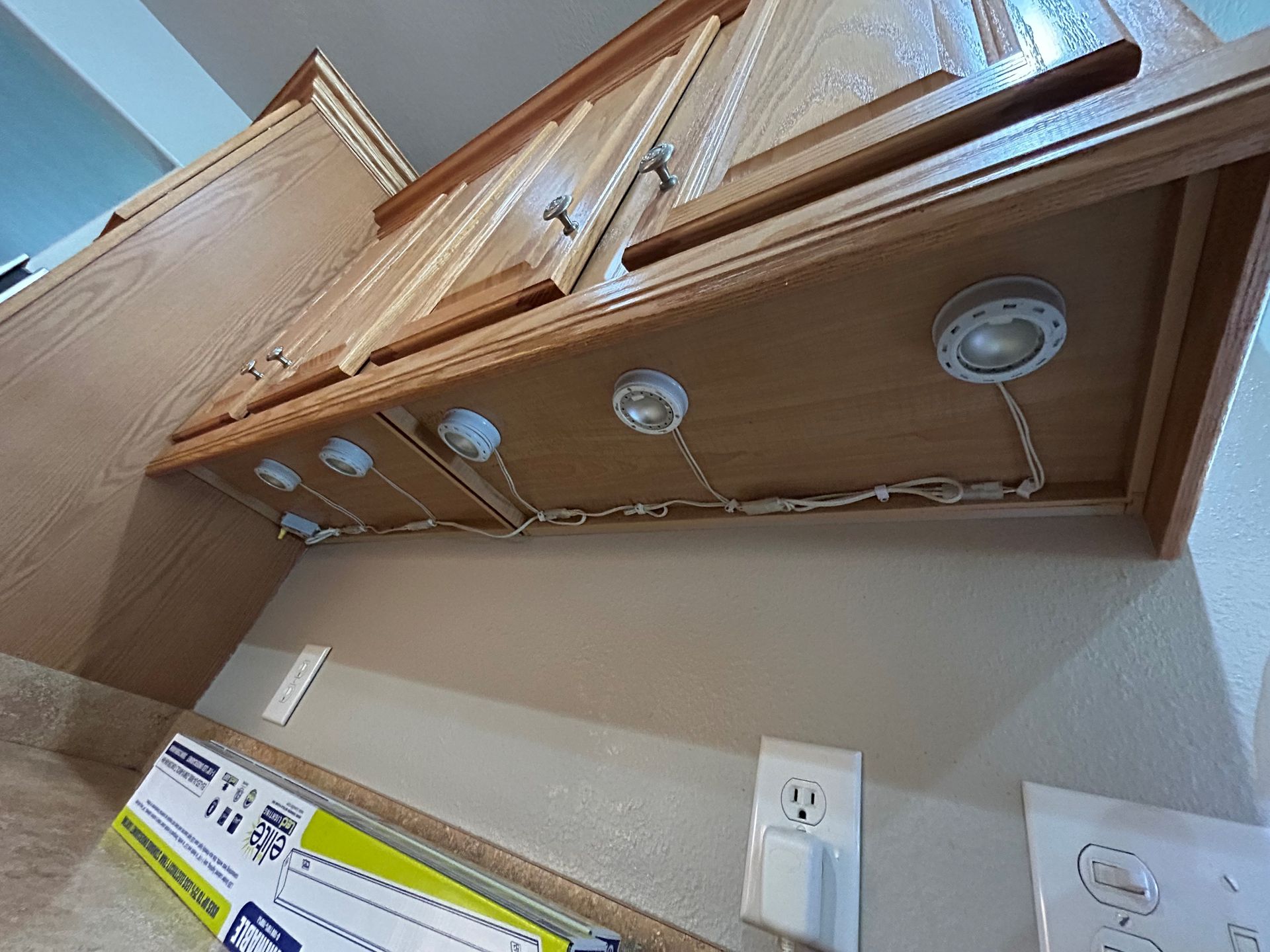 A kitchen with wooden cabinets and a box of cling film on the counter.
