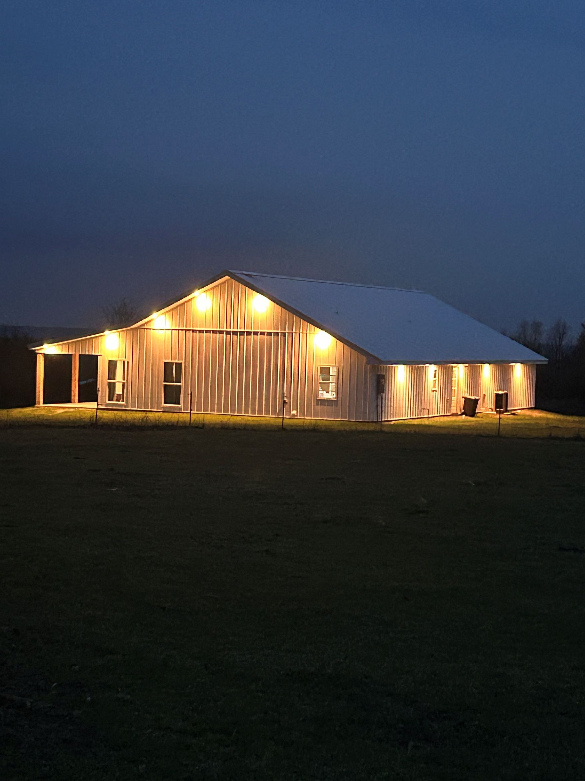 A barn is lit up at night in a field