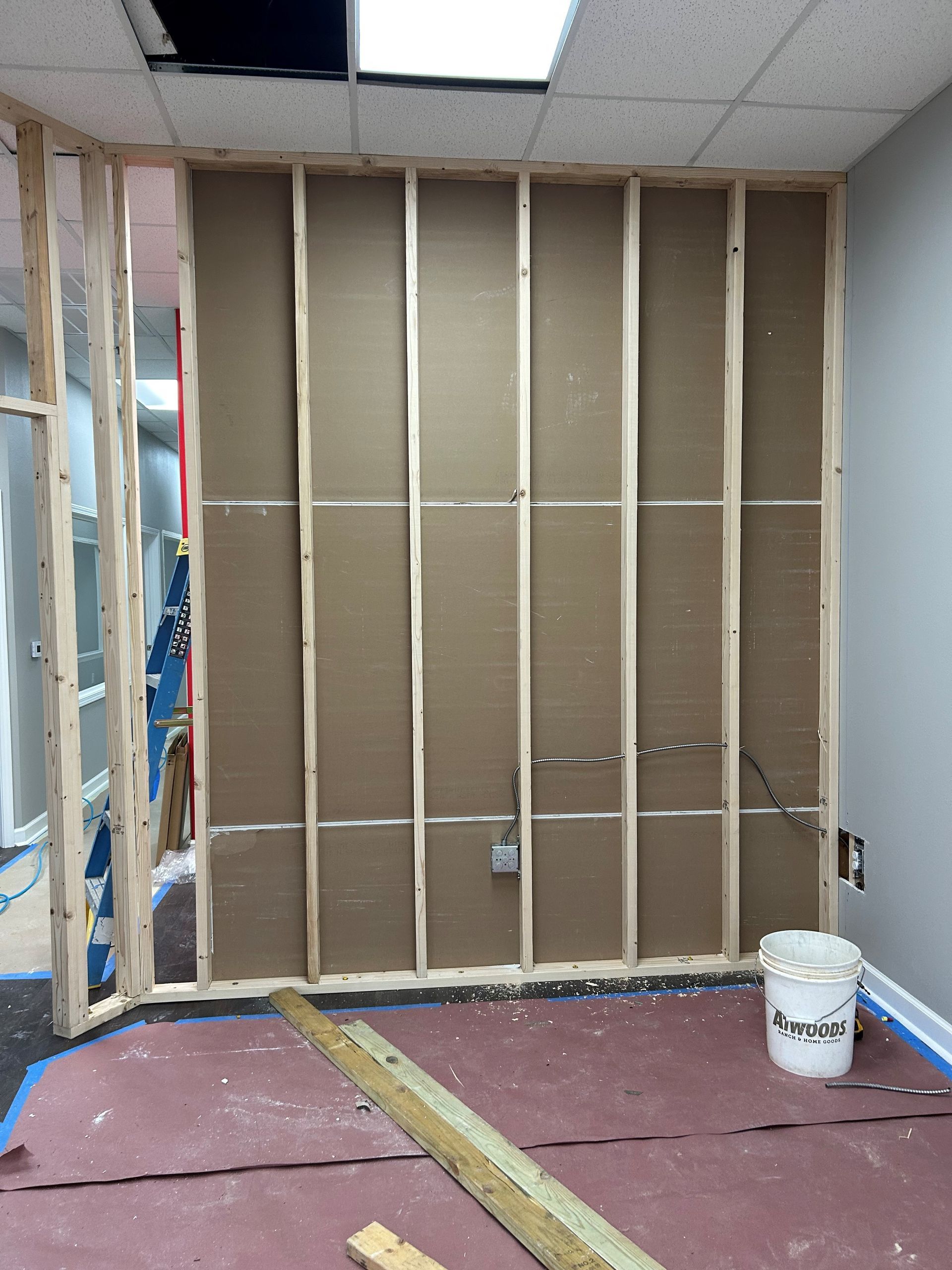 A room under construction with a bucket of paint on the floor