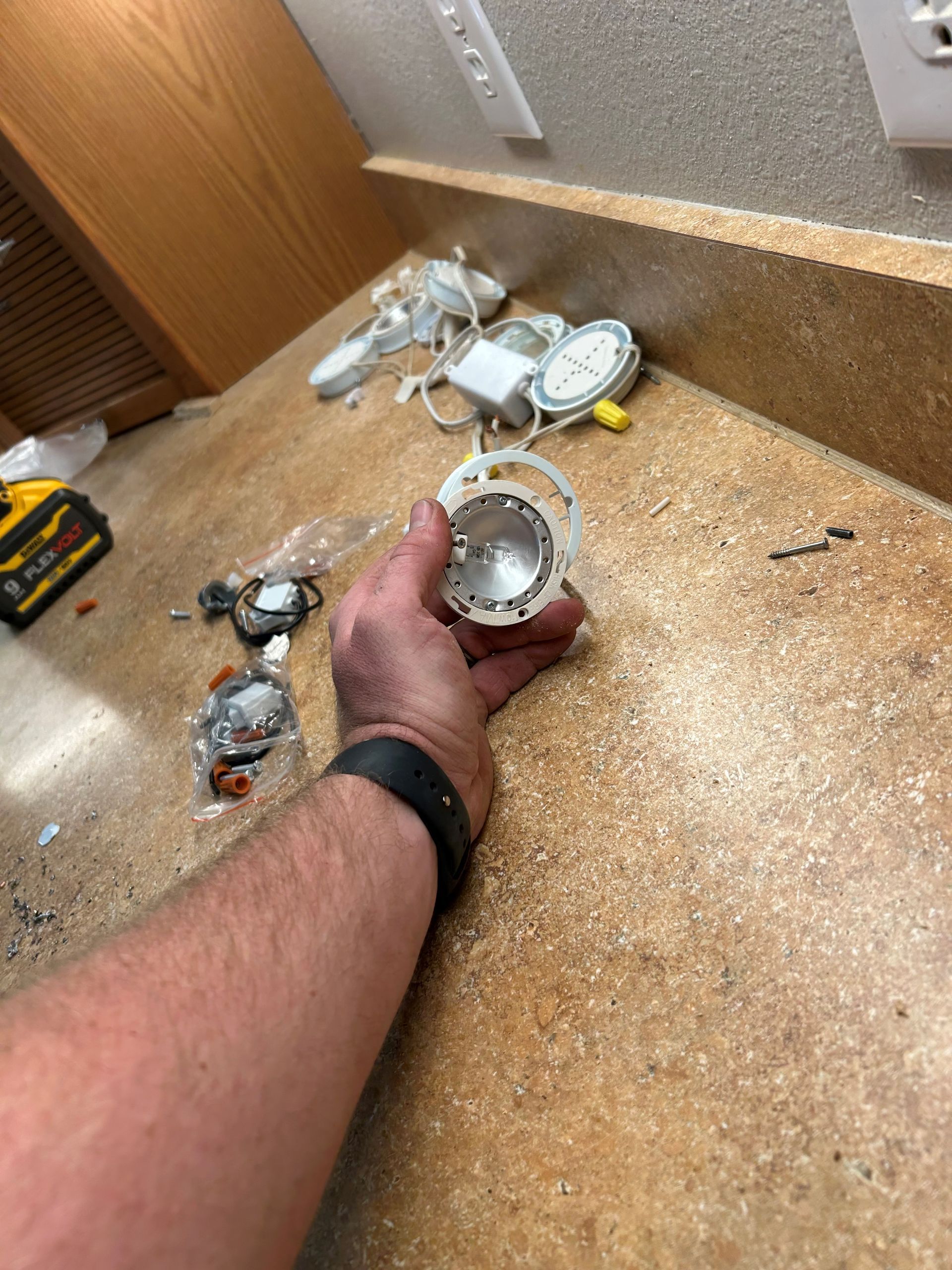 A person is holding a light bulb in their hand on a counter.