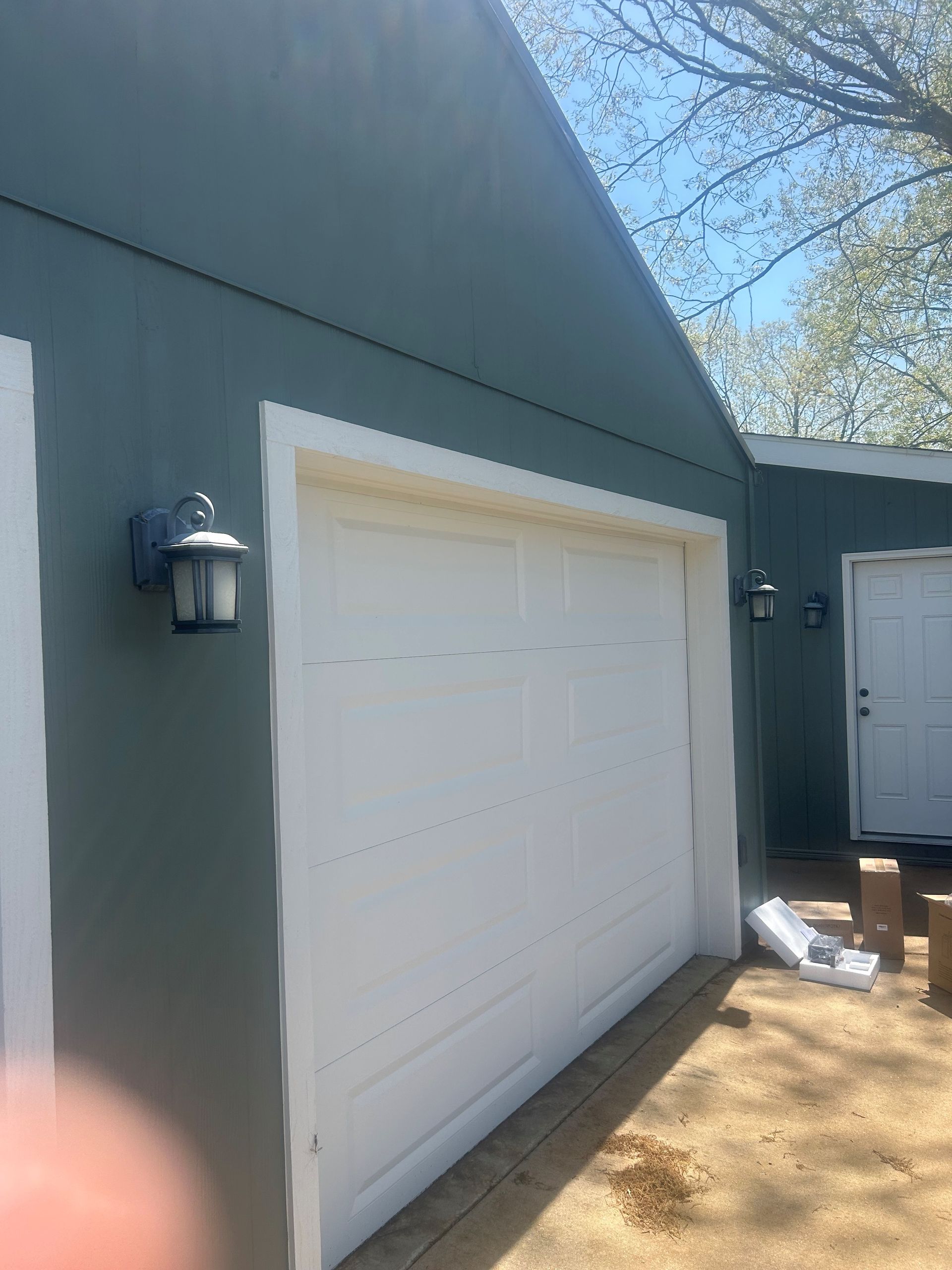 A white garage door is sitting on the side of a house.