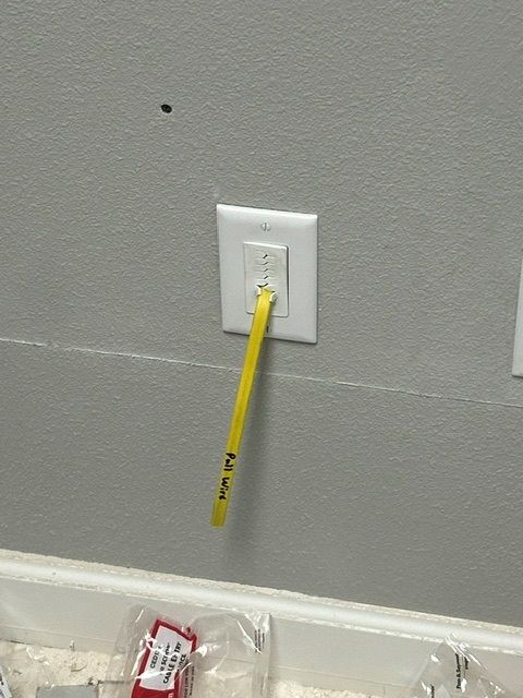 A yellow toothbrush is plugged into a wall outlet