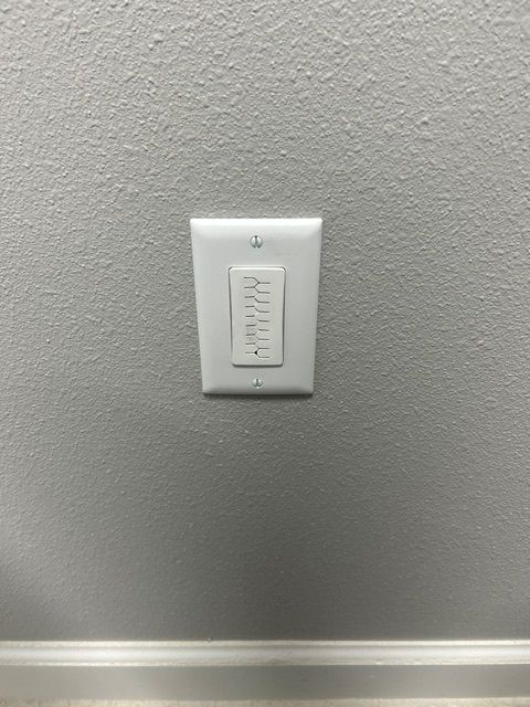 A white light switch is mounted on a gray wall.