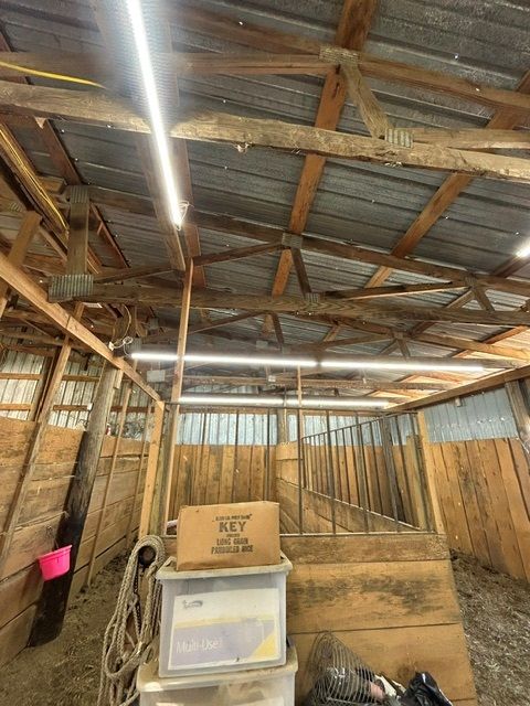 The inside of a barn with wooden beams and a metal roof.
