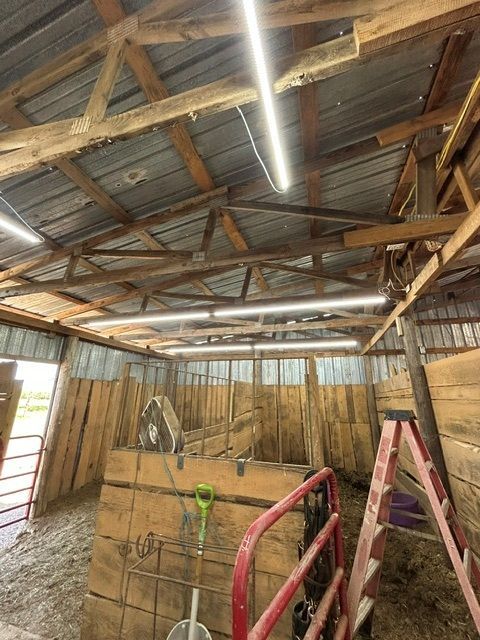 A wooden barn with a ladder and a fan in it.