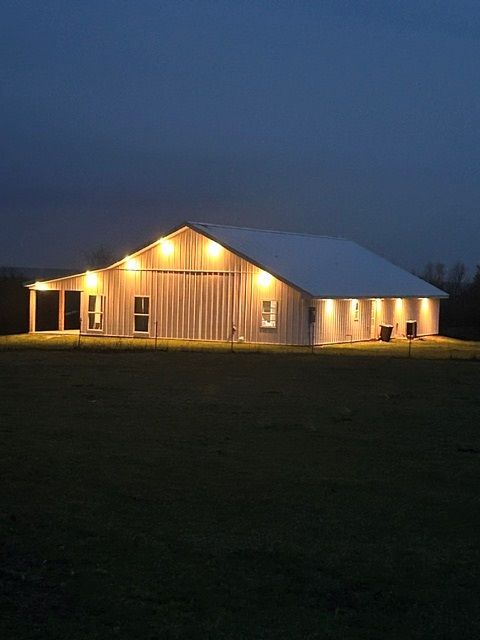 A barn is lit up at night in a field