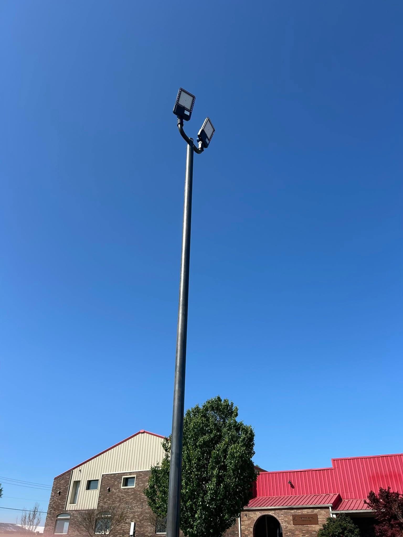 A tall pole with two lights on it is in front of a building with a red roof.