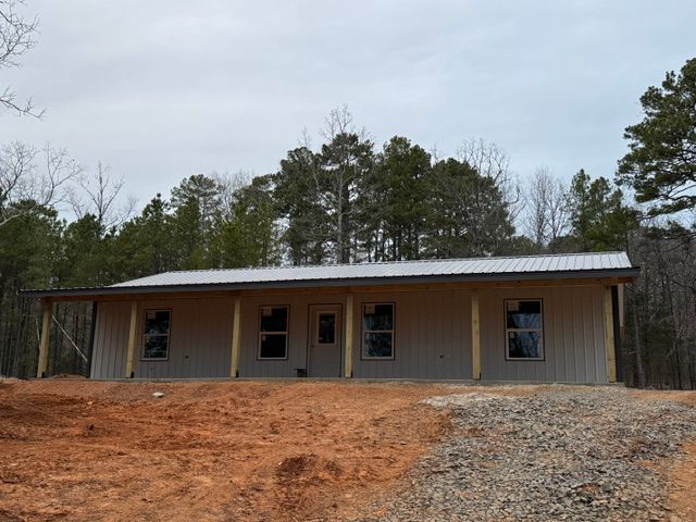 A house is sitting on top of a dirt hill in the middle of a forest.