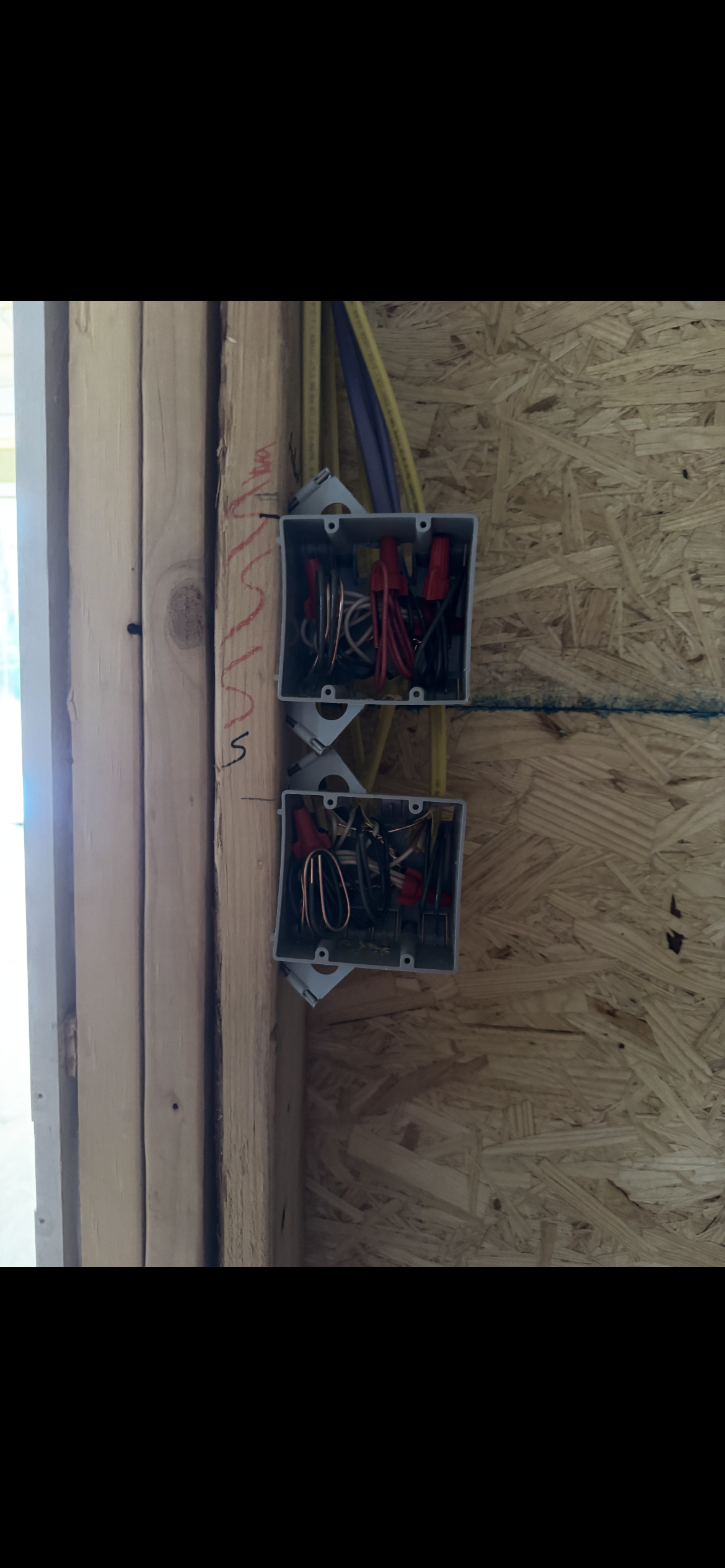 Two electrical boxes are hanging on a wooden wall.