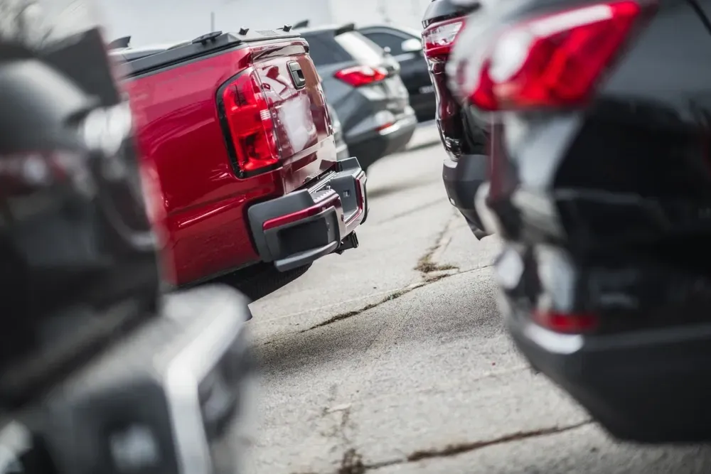 Close-up view of the rear ends of several vehicles parked in a line on a concrete lot, including a prominent red truck. — Murwillumbah Motor Wreckers in South Murwillumbah, NSW