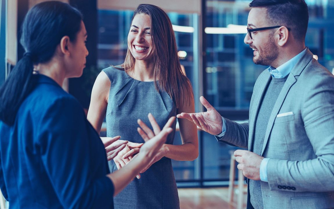 A group of business people are talking to each other in an office.