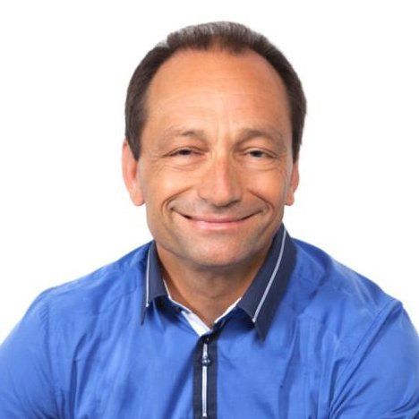 A man in a blue shirt is smiling for the camera