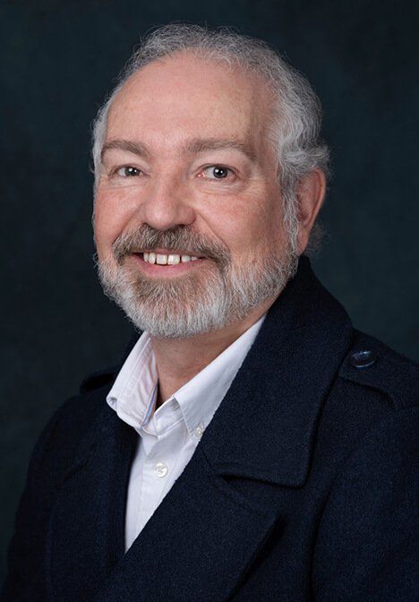 A man with a beard and a blue jacket is smiling for the camera.