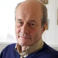 A man wearing  a blue shirt is smiling for the camera.
