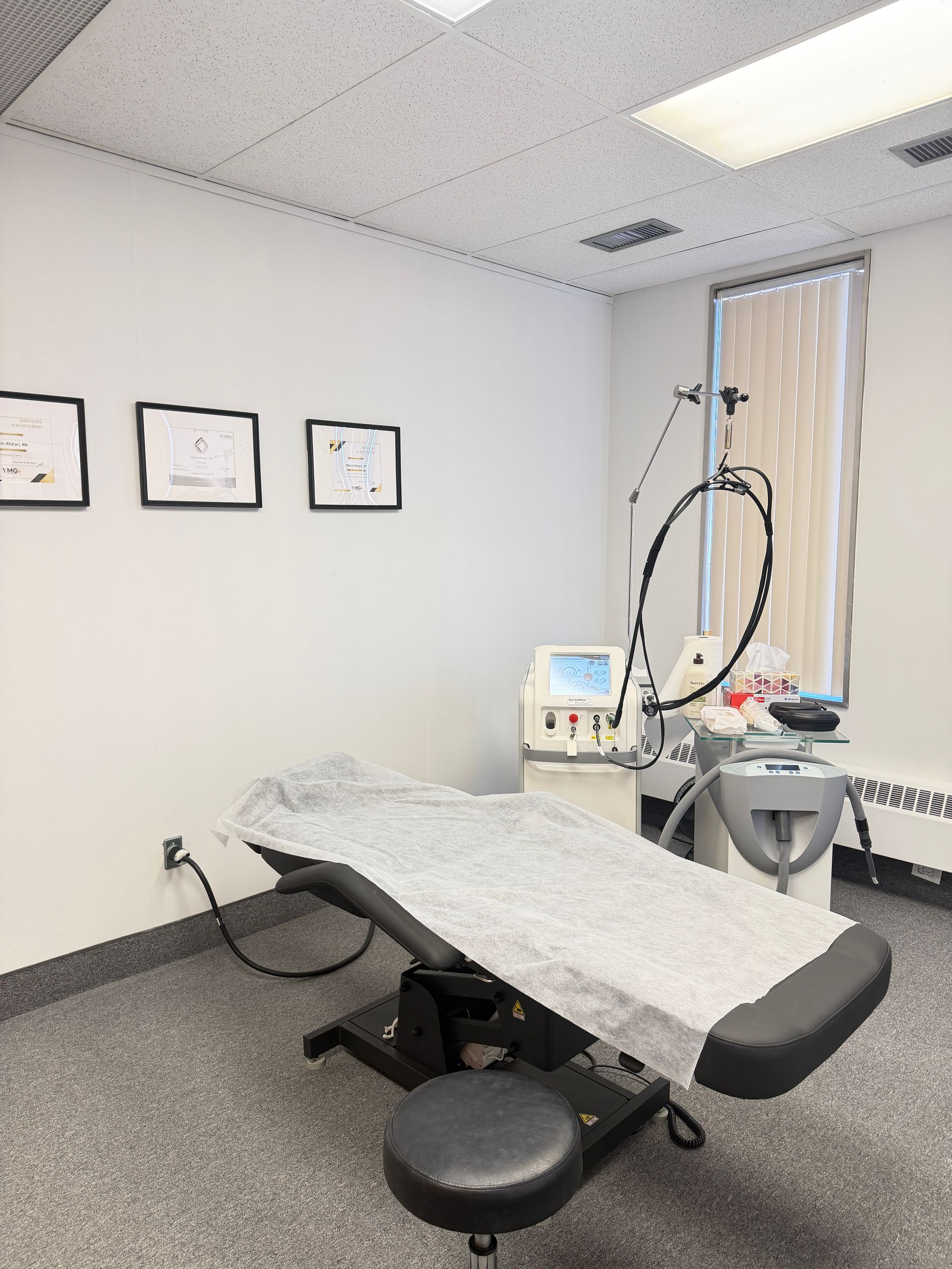 Medical exam room with treatment table, stool, monitor, and wall-mounted equipment