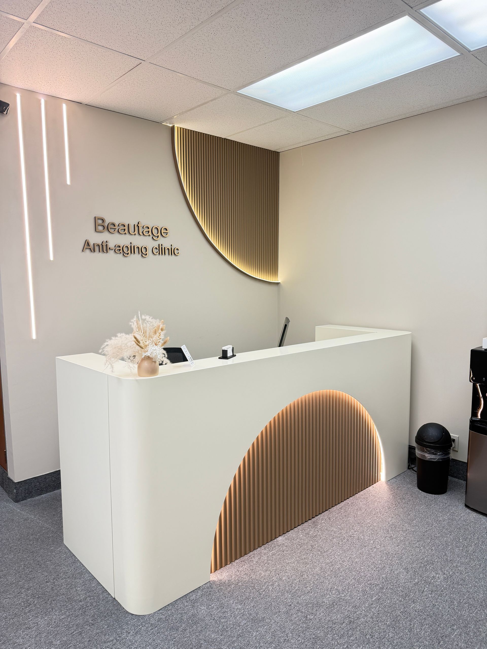 Modern beauty reception desk with white and wood design, soft lighting, and a minimalist interior
