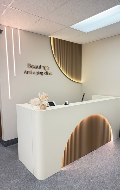 Minimalist beauty reception desk with warm wood accent and soft lighting in a modern clinic lobby