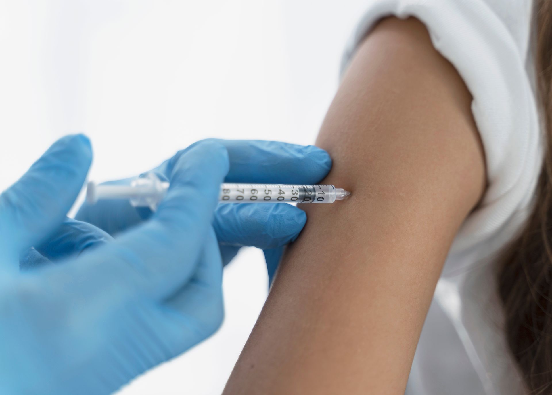 Gloved hand giving an injection in a person’s upper arm