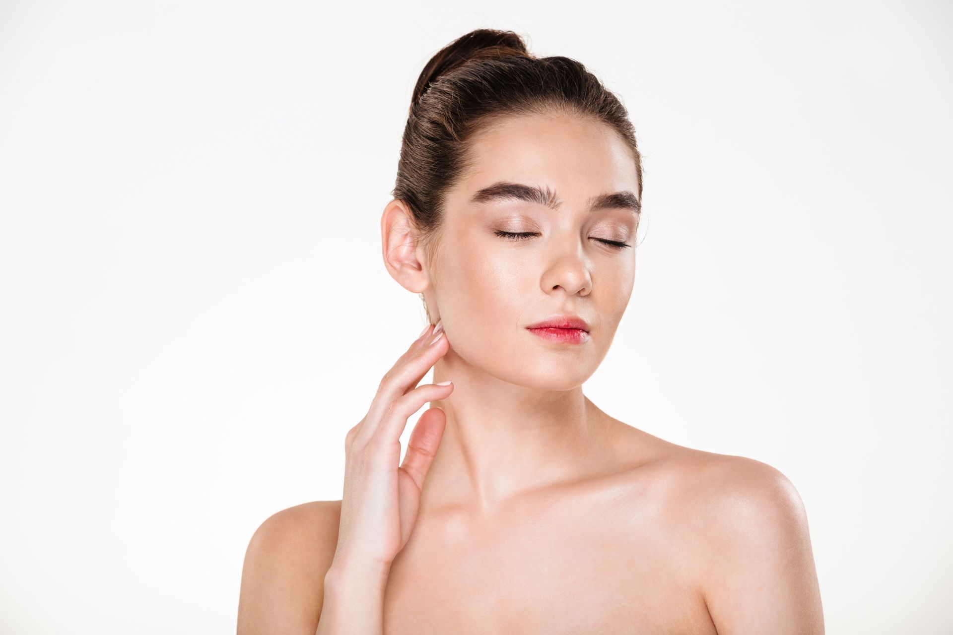 Woman posing with eyes closed, hand gently touching her neck against a plain white background