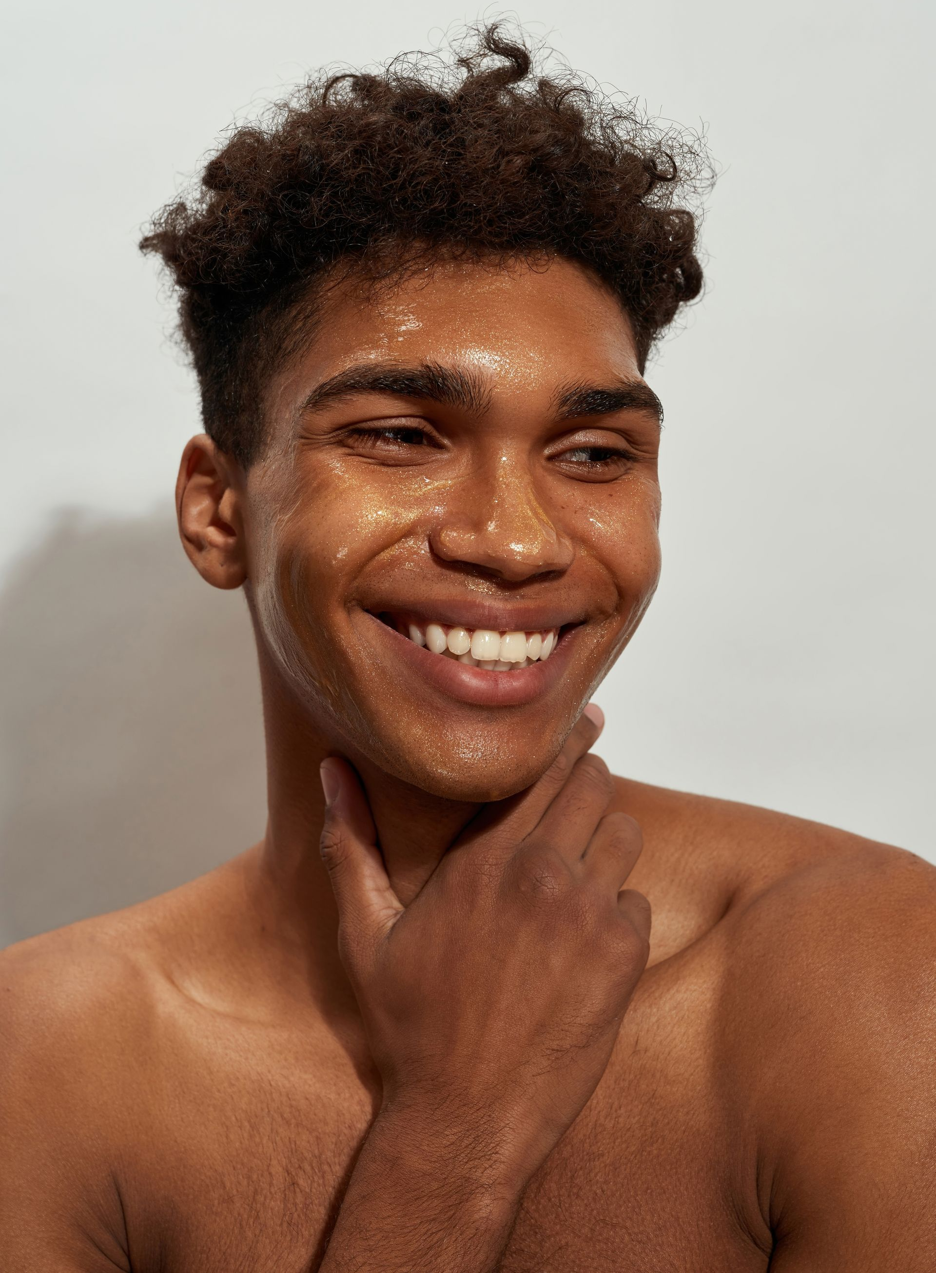 Portrait of a person in a white top, resting their chin on their hand against a light background