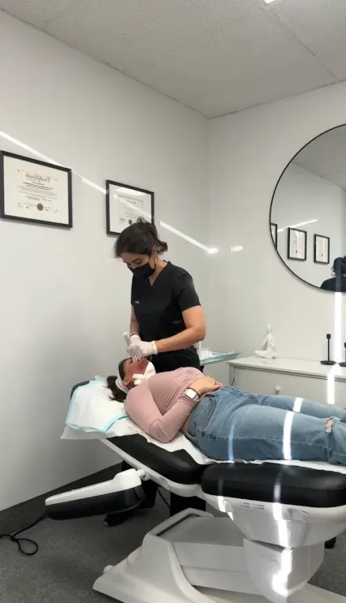 Person receiving a dental treatment in a modern clinic, reclining in a chair while a dentist works nearby