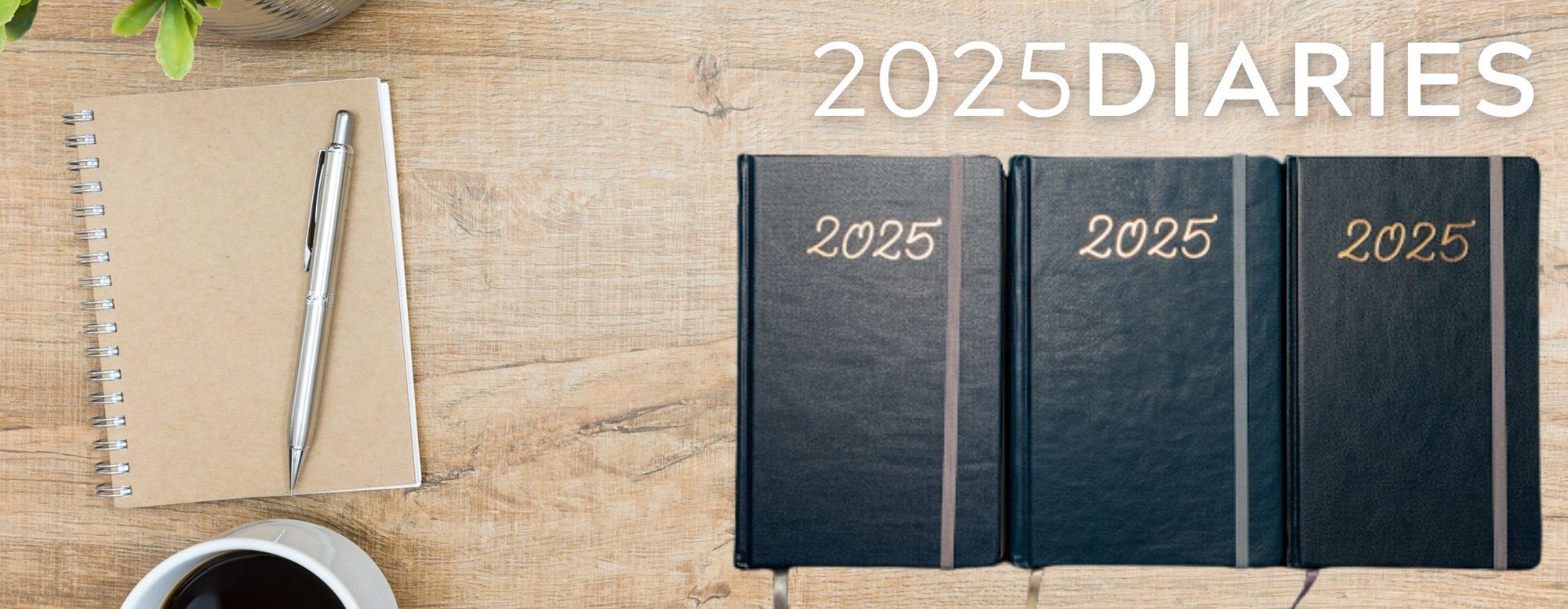 Three diaries are sitting on a wooden table next to a cup of coffee.