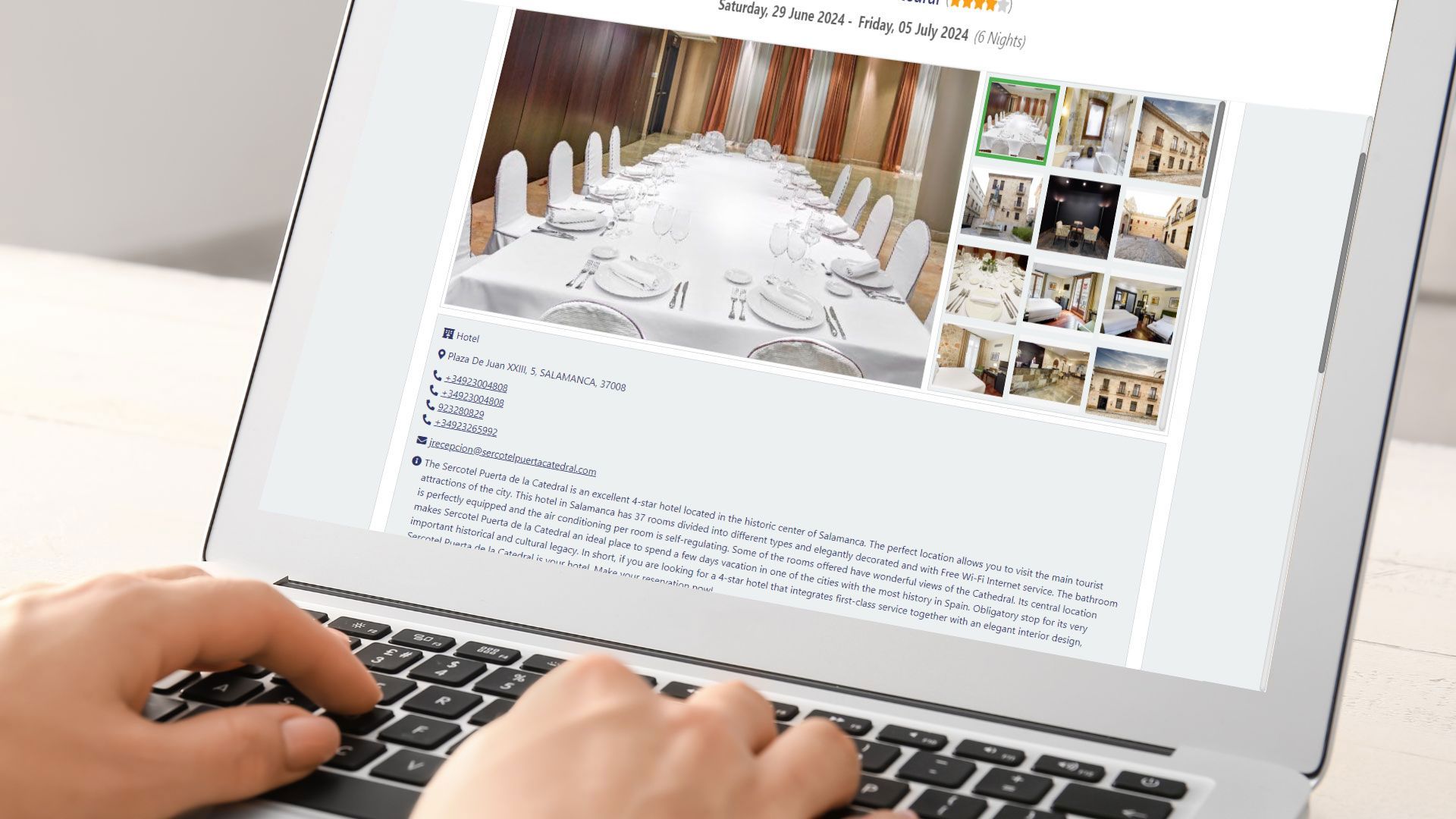 Person typing on a laptop, browsing a website with pictures of an event hall.