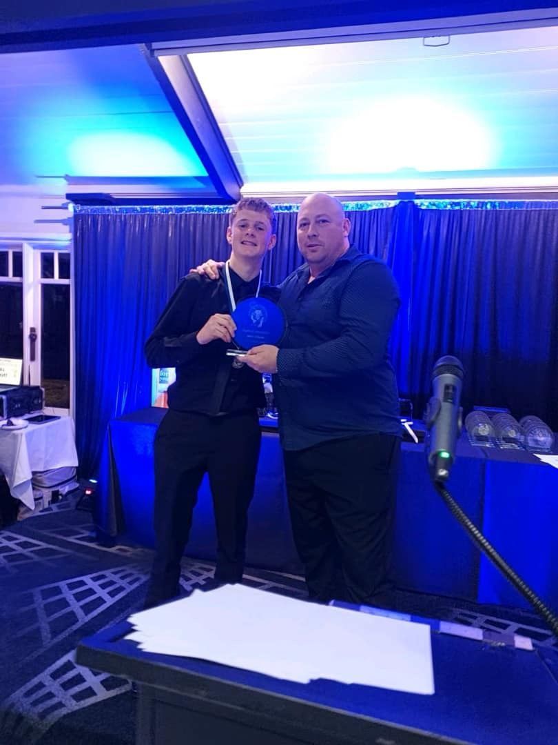 Two men are standing next to each other in a room holding a blue object.