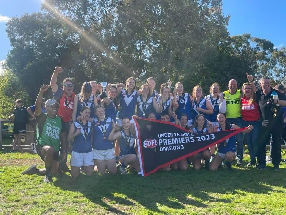 A group of people are posing for a picture while holding a flag.