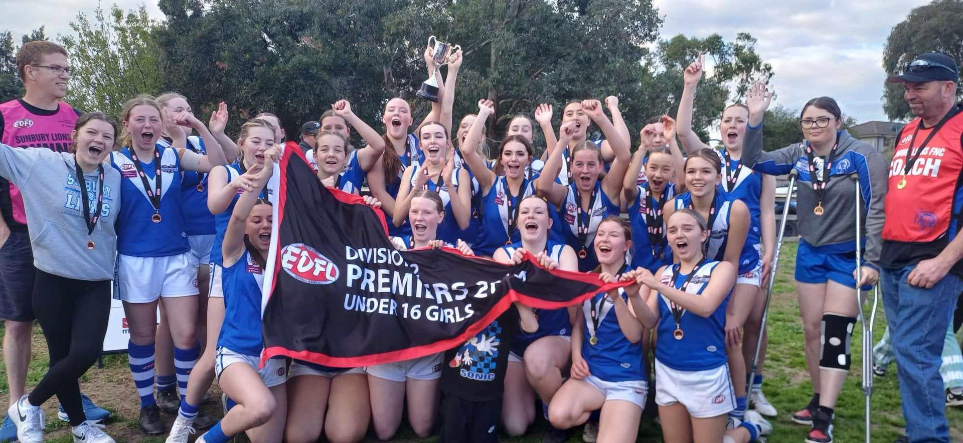 A group of young girls are posing for a picture while holding a flag.