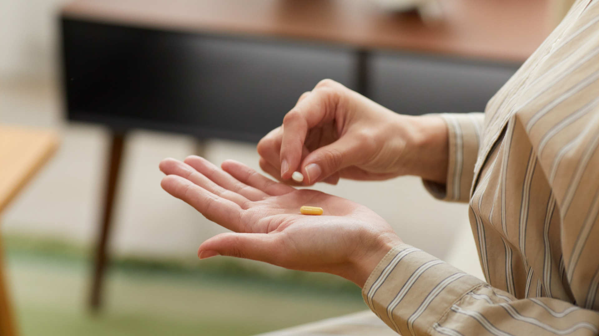 Person holding pills in their hand, indoors.