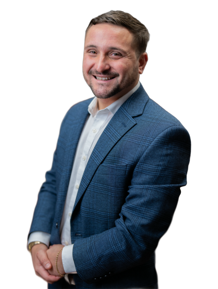 A woman wearing a sweater and a heart necklace is smiling at the camera.