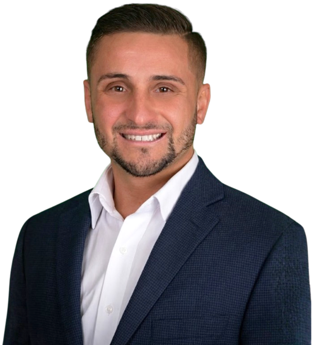 A woman wearing a sweater and a heart necklace is smiling at the camera.