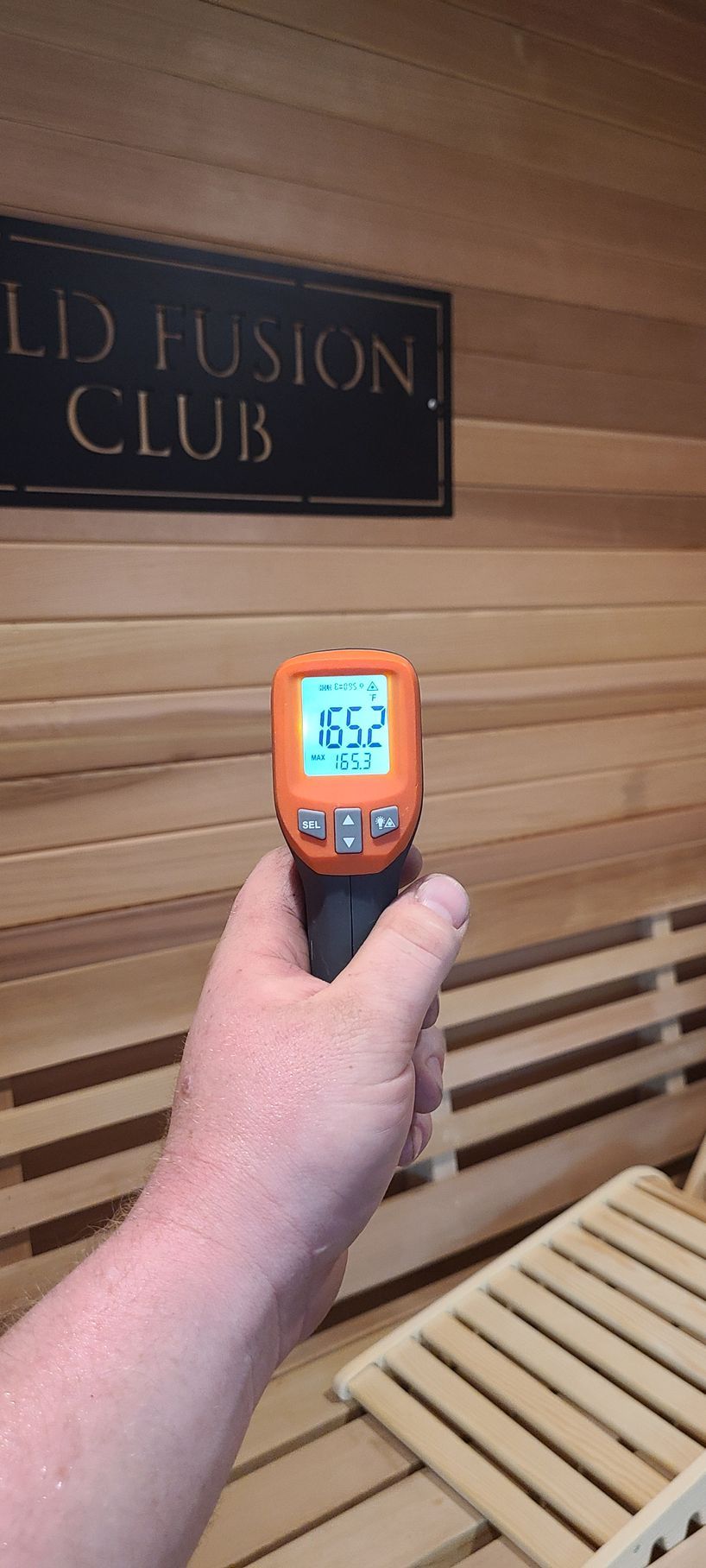A person is holding a thermometer in a sauna.