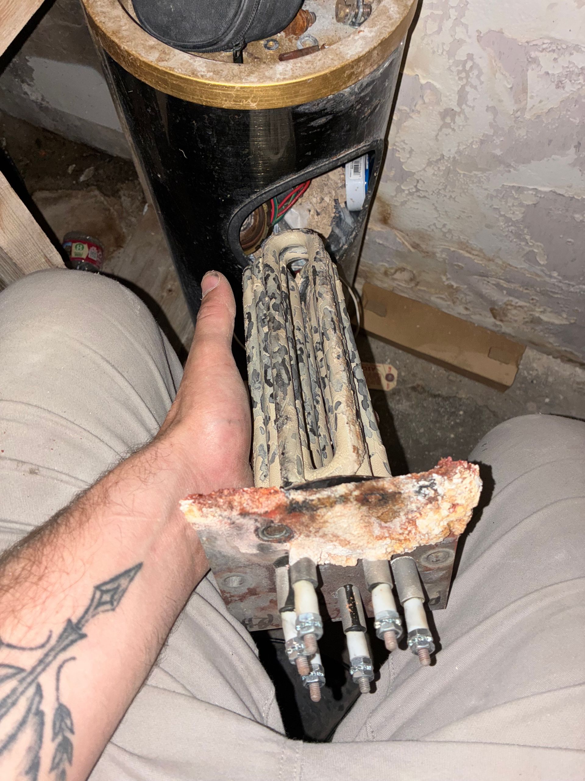 A person with a tattoo on their arm is holding a piece of pizza in their hand.