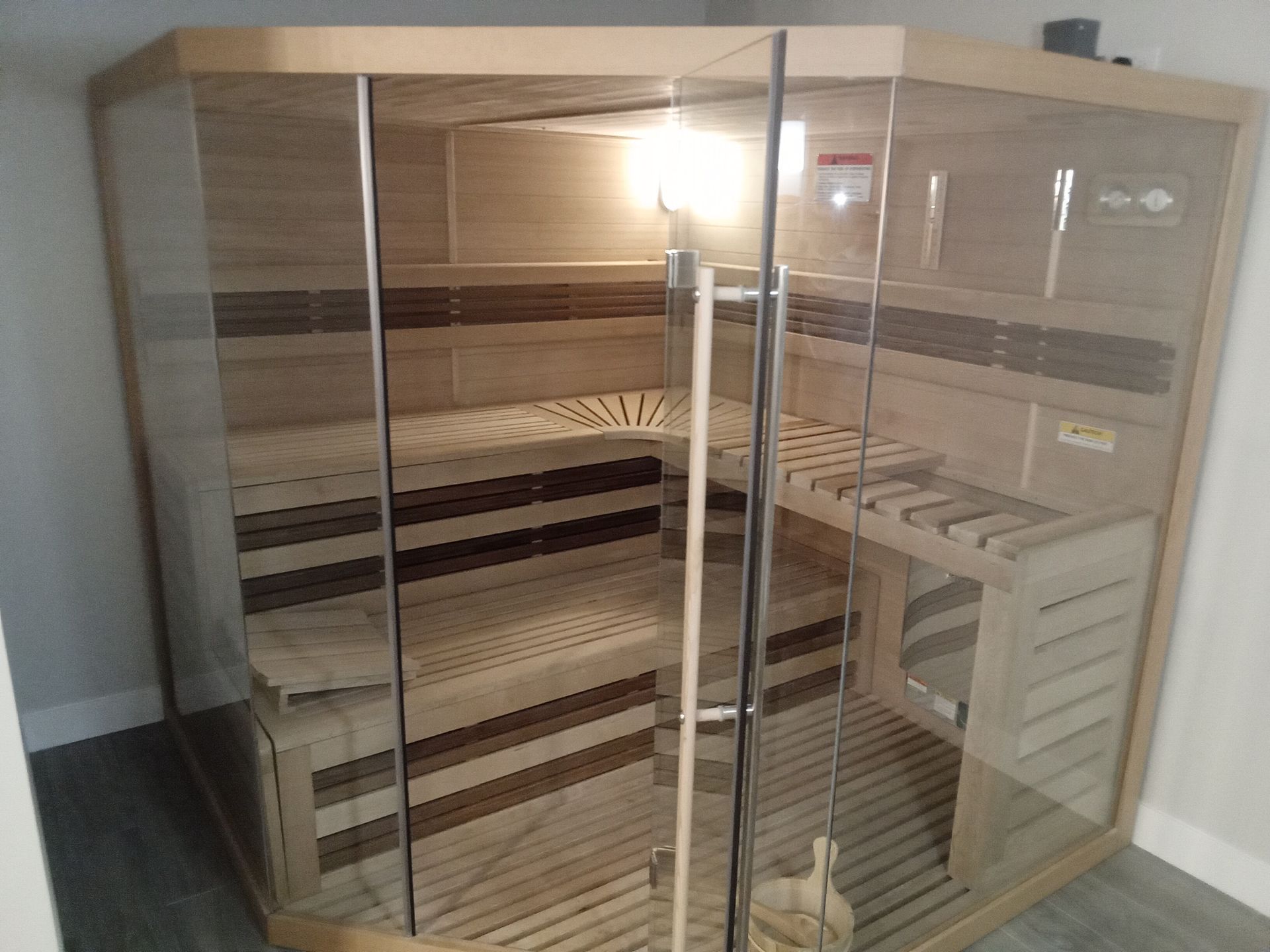 A wooden sauna with a glass door is sitting in a room.