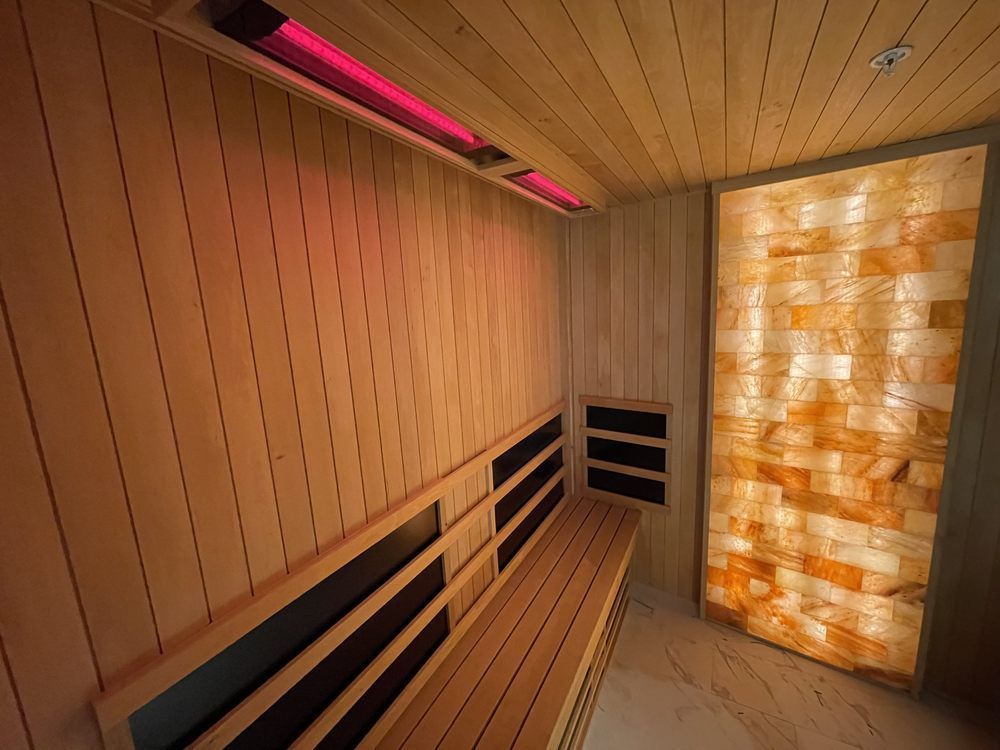 A wooden sauna with a bench and a brick wall.