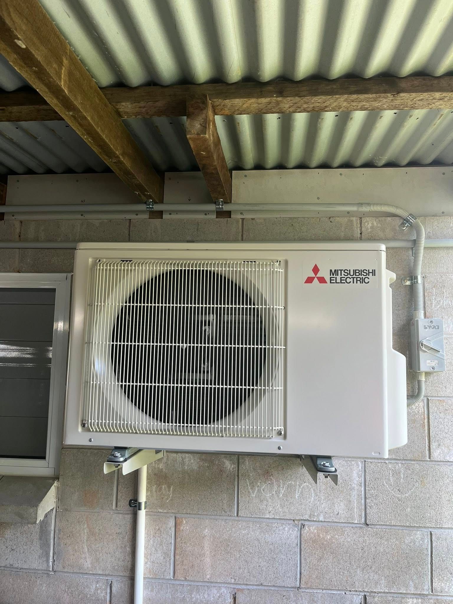 Outdoor Air Conditioner Unit Beside a Sunlit Window on a Tiled Balcony — Topspark Electrical FNQ in Mareeba, QLD