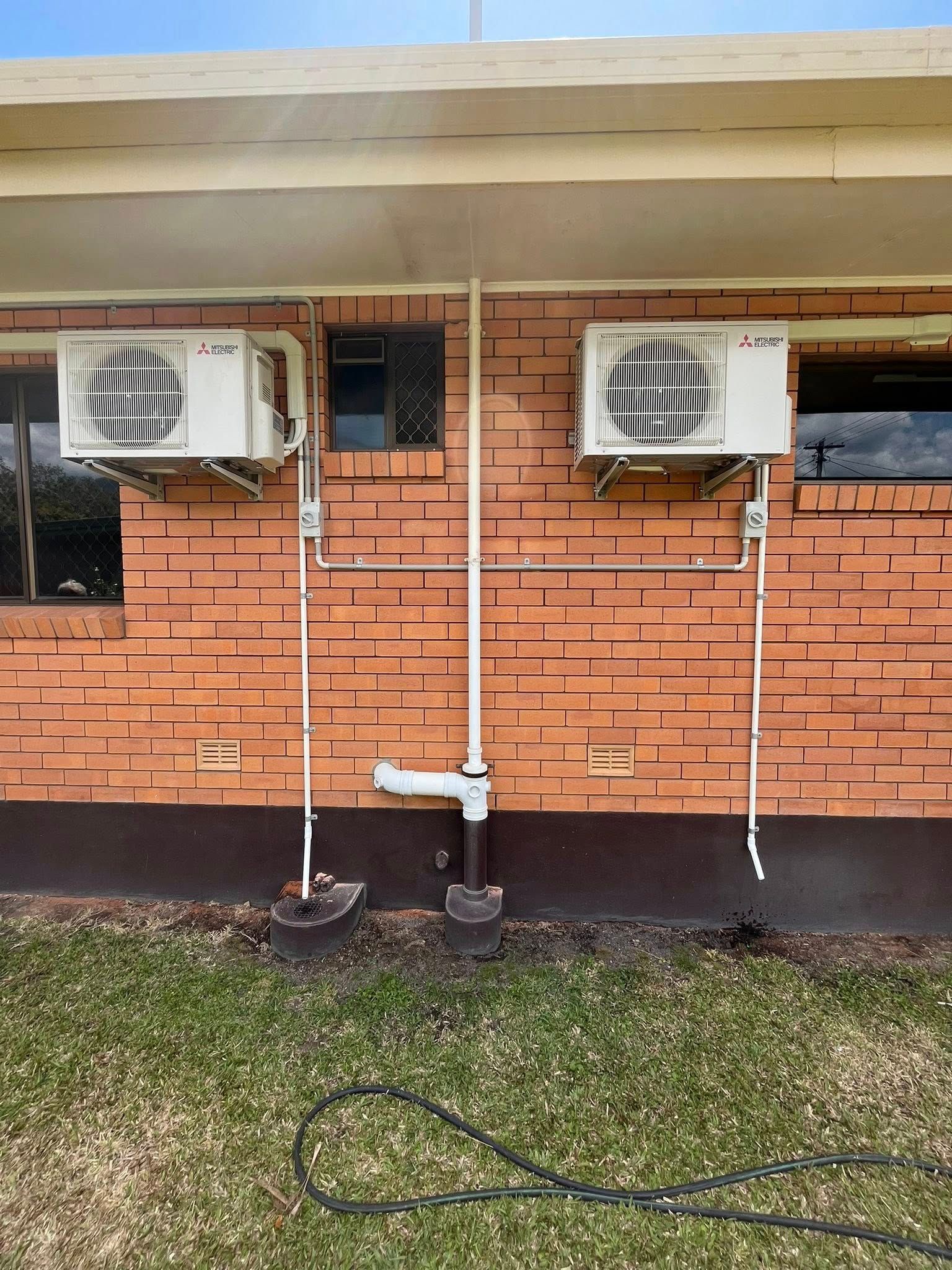 Two Wall-mounted Air Conditioners With Exposed White Pipes — Topspark Electrical FNQ in Mission Beach, QLD