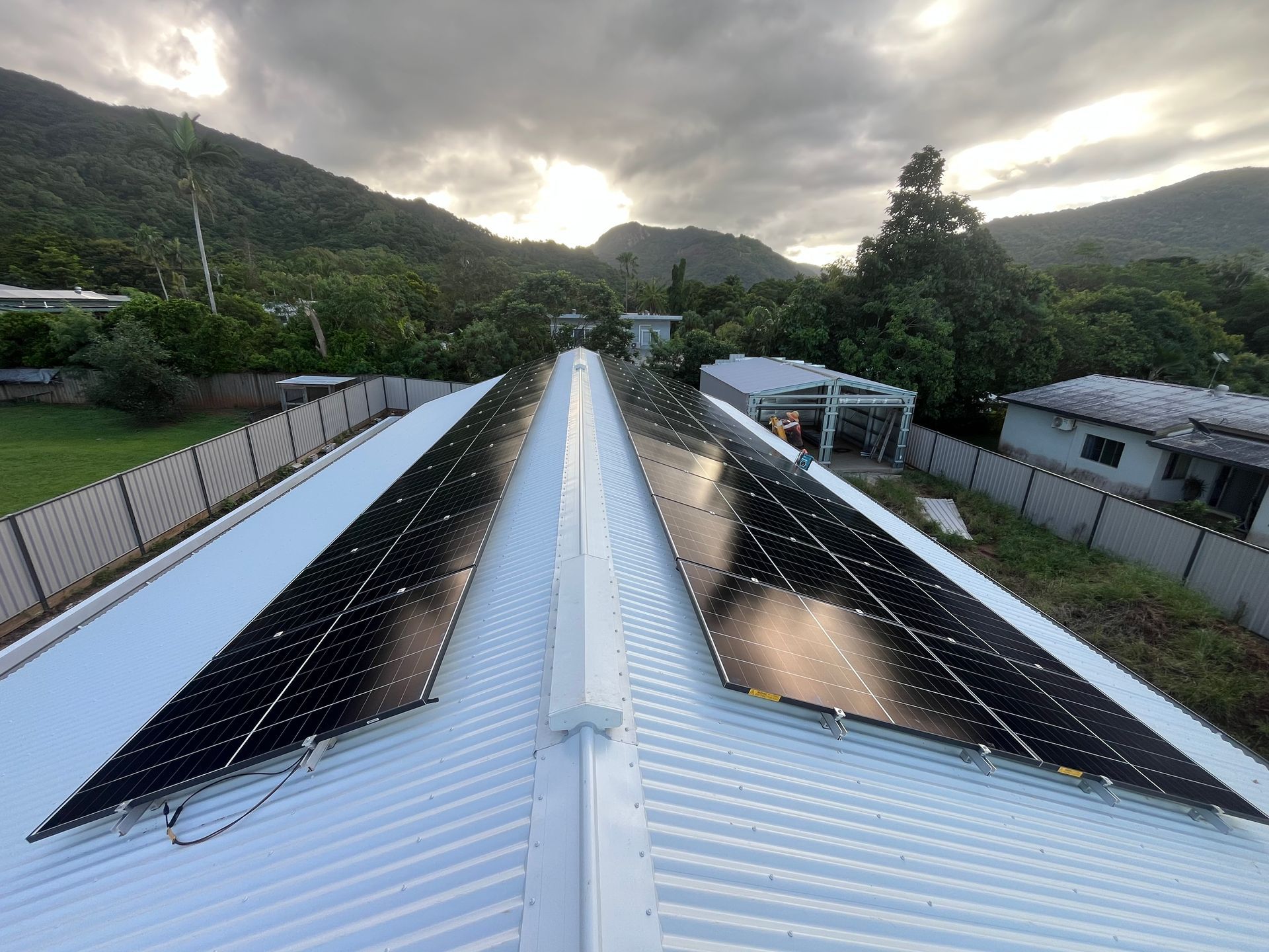 Solar Panels Mounted on a Metal Roof Beside a Green Hillside — Topspark Electrical FNQ in Mission Beach, QLD