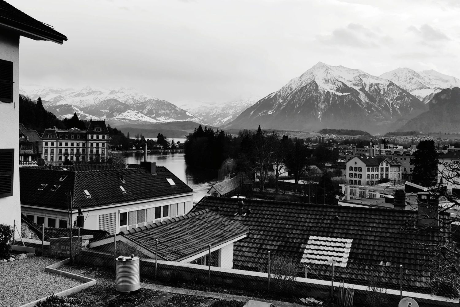 Im Vordergrund ein traditionelles Holzchalet, im Hintergrund ein weißes, historisches Schloss, eingebettet in die Berge.