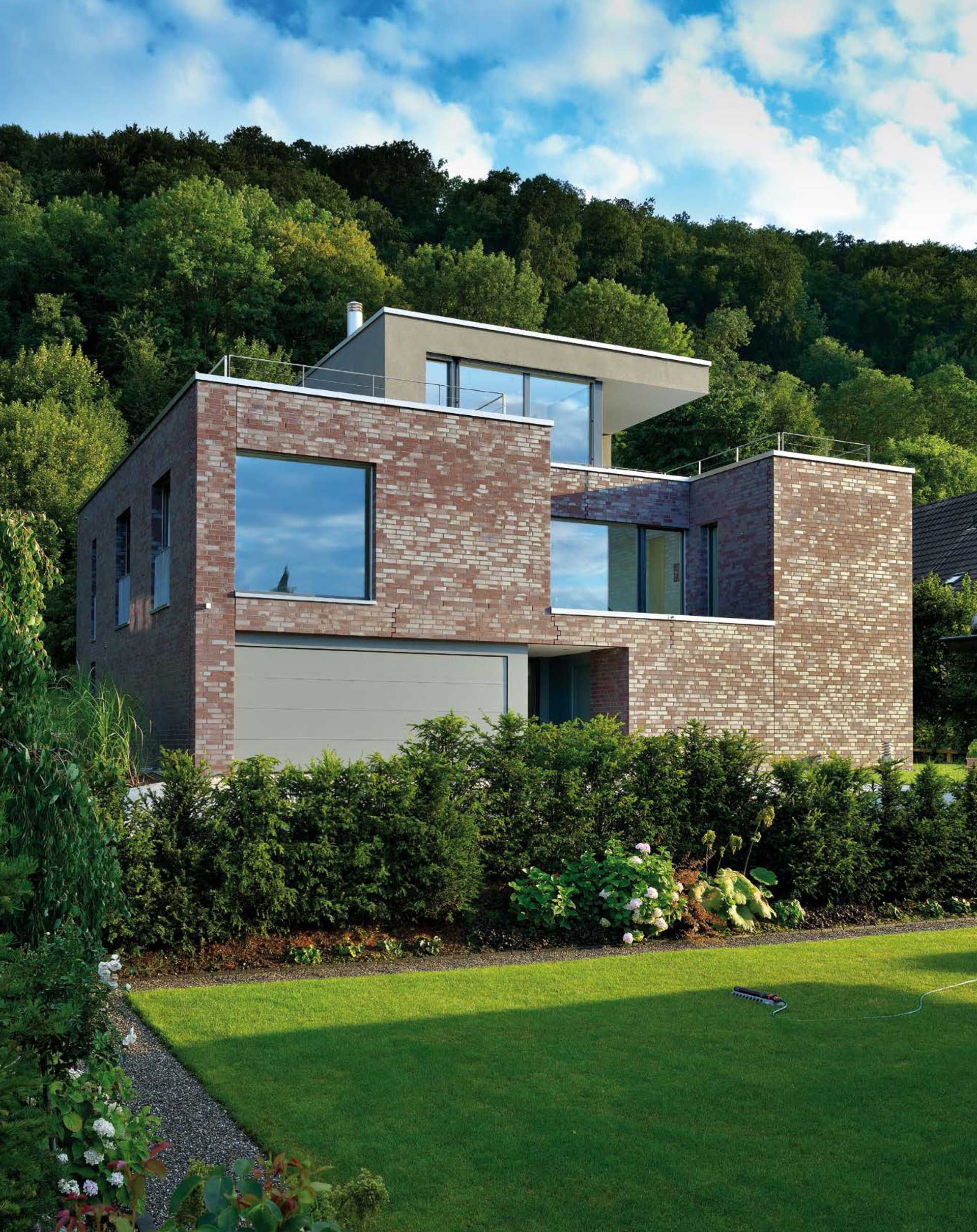 Ein großes Backsteinhaus liegt auf einem üppig grünen Hügel