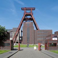 Ein großes Backsteingebäude mit einem roten Turm davor.