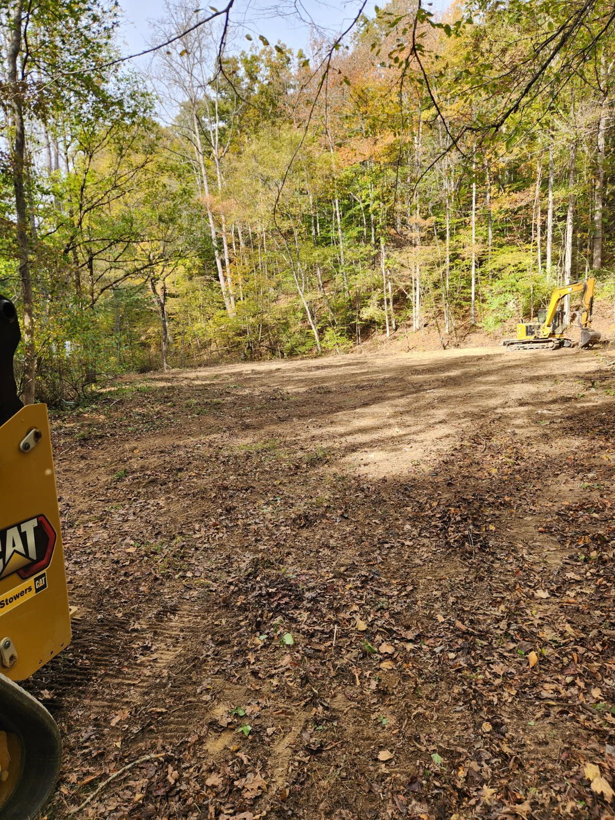 Orange excavator on a construction site under a partly cloudy sky.